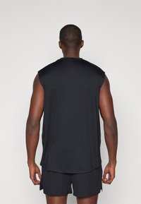 Black sleeveless athletic top made of textured fabric, featuring a round neck and a relaxed fit, paired with matching black shorts.