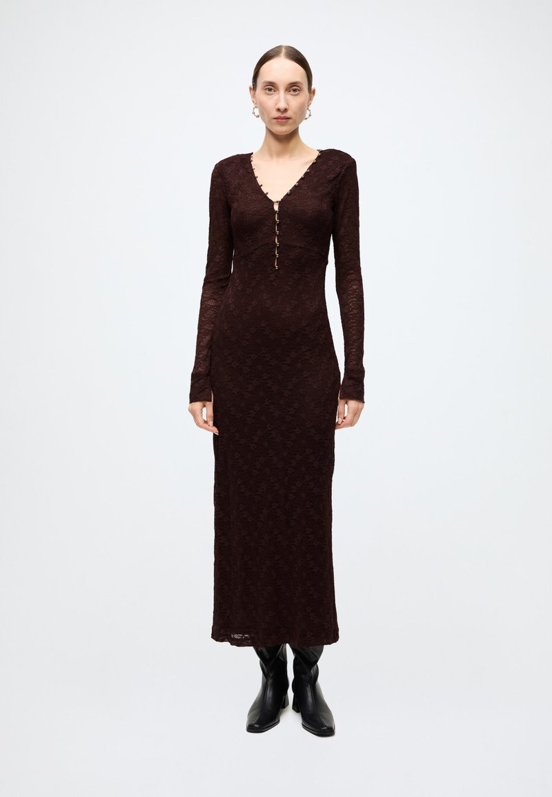 Burgundy long-sleeve lace dress with a V-neck, featuring a button front and a streamlined silhouette, paired with black ankle boots.