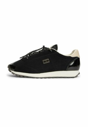 Sort lav-sko sneakers med hvid sål, sorte og hvide snørebånd, beige hælkappe og lille logo på sidepanelet.