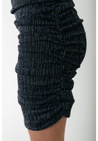 Robe sombre ajustée en tissu texturé avec des rayures verticales argentées et des fronces sur les côtés pour plus de profondeur.