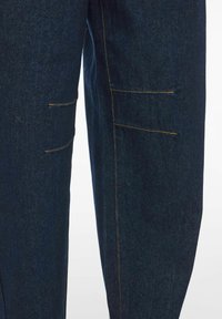 Dark blue denim pants featuring two horizontal pockets with contrasting yellow stitching. The fabric has a smooth, textured appearance.