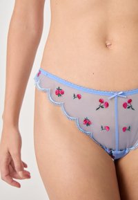 Mutande in rete celeste con ciliegie rosse ricamate, bordi scallop e rifinitura in picot. Presentano un piccolo fiocco al centro frontale.
