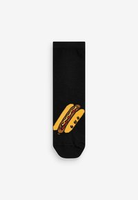 Sorte sokker med et grafisk motiv af to gule hotdogs med røde og brune accenter. Strikket tekstur, standard ankel-længde.