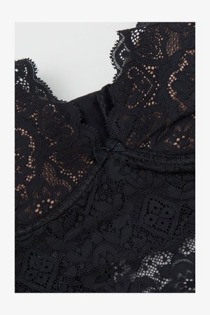 Zwarte kanten stof met bloemmotieven, voorzien van een geschulpte rand en een satijnen strikdetail in het midden. Zachte en delicate textuur.