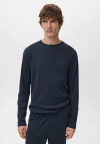 Dunkelblaues Langarm-Henley-Shirt mit gerippter Textur, drei Knöpfen und Rundhalsausschnitt, kombiniert mit einer passenden dunklen Hose.