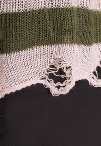 Gebreid sweater met horizontale strepen in olijfgroen en lichtroze, voorzien van een versleten zoom en losse draadjes. Zwarte stof eronder zichtbaar.