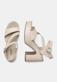 Sandali beige con tacco alto, dettagli incrociati, chiusura a fibbia e suola a piattaforma voluminosa. Finitura in pelle liscia opaca.