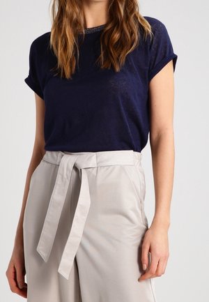 Marineblå kortærmet t-shirt kombineret med lysegrå højtaljede bukser med en bundet bælte og en glat tekstur.