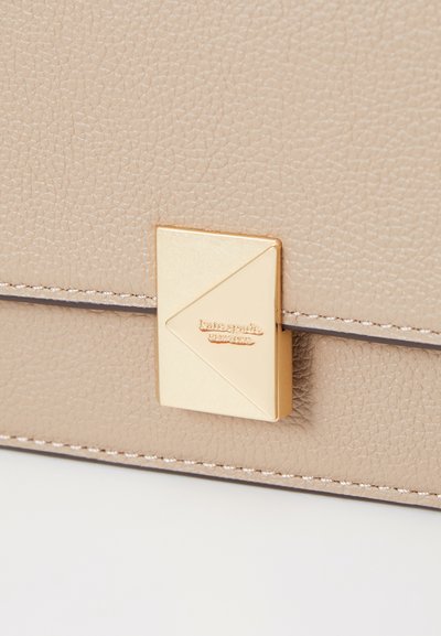 Beige textured leather bag with a gold-tone triangular clasp featuring brand engraving. Contrasting stitching along the edges.