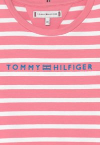 Gestreiftes T-Shirt in Pink und Weiß mit Rundhalsausschnitt. Zeigt das "TOMMY HILFIGER" Logo in Blau auf der Brust. Aus weichem Baumwollstoff.