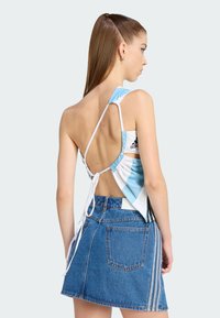 Μπλε και λευκή ριγέ αμάνικη μπλούζα με σχέδιο δέσιμο στην πλάτη, συνδυασμένη με μίνι φούστα από τζιν με ρίγες στο πλάι και τσέπες.