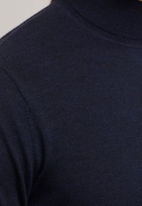 Námorně modrý rolák vyrobený z měkké pleteniny s hladkým povrchem a přiléhavým střihem, se žebrovaným límcem a manžetami.