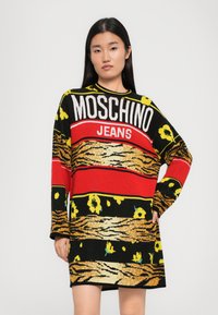 Juostos suknelė juodos, raudonos ir geltonos spalvų su "MOSCHINO JEANS" logotipu. Pasipuošusi gėlių ir gyvūnų raštais, ilgomis rankovėmis ir laisvu siluetu.