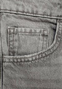 Sivi denimski material z manjšo sprednjo žepom in vidno šivanjem. Tekstura je rahlo groba s opaznim twill vzorcem.