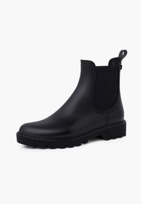 Botas Chelsea de goma negras con un upper suave, paneles laterales elásticos, suela robusta con relieve y tirador para facilitar el calzado.
