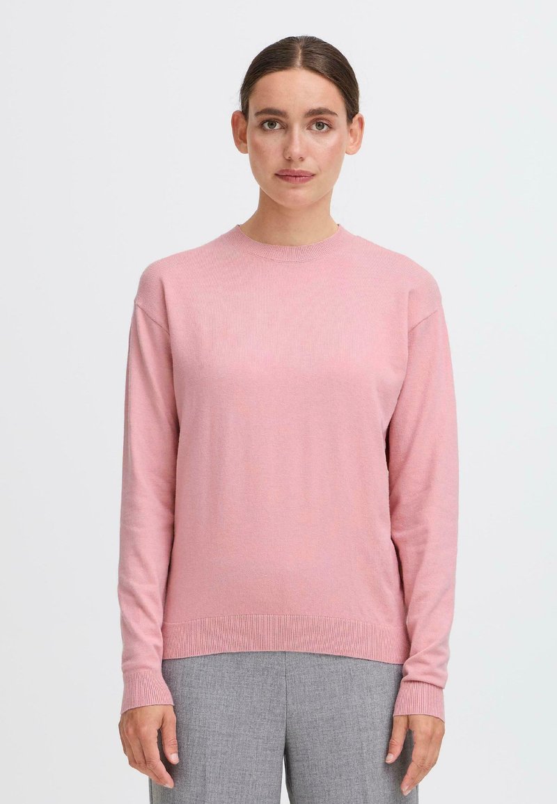 Rosa stickad tröja med lång ärm, rund halsringning och ribbade detaljer vid ärmbladen och nederkant. Slät textur, avslappnad passform.
