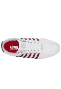 Weißer Sportschuh mit roten und silbernen Akzenten, ausgestattet mit einer strukturierten Zehenkappe, sechs weißen Schnürsenkeln und einem gepolsterten Kragen. Rotes Logo-Innenfutter sichtbar.