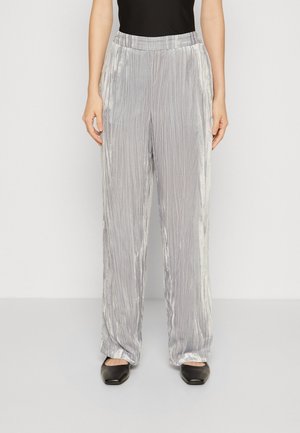 Pantalons larges plissés argentés avec une taille élastique, en tissu texturé et finition lisse, assortis à des chaussures noires à enfiler.