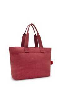 Bolso de tela rojo con dos asas trenzadas, de forma rectangular, superficie texturizada, que presenta un acento de pom-pom en un lado.