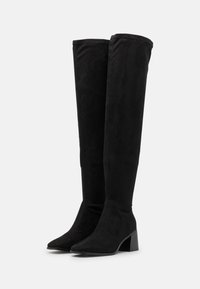 Zwarte over-de-knie laarzen van zacht suede, met een puntige neus en een getextureerde blokhak. Elegante vormgeving met een aansluitende silhouet.