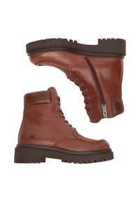 Hnědé kožené šněrovací boty s polstrovaným límcem, bočním zipem a silnou černou robustní podrážkou, zobrazené z bočního a spodního pohledu.