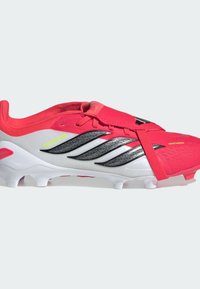 Ποδοσφαιρικό παπούτσι με φωτεινό ροζ επάνω μέρος, ασημί λεπτομέρειες και μαύρες ρίγες. Διαθέτει υφή στην επιφάνεια και ασφαλές λουράκι πάνω από τα κορδόνια.