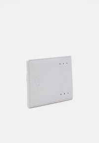 Cartera gris claro con una textura suave, bordes redondeados, logo en relieve y tres agujeros de ventilación en la parte superior. Diseño rectangular compacto.