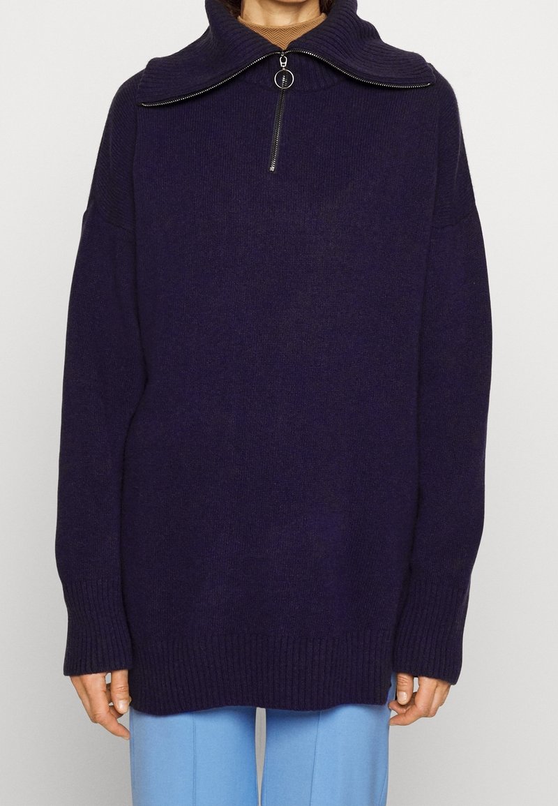 Purple knit sweater with a high collar, zip closure, and ribbed cuffs. Features a loose fit and slightly textured fabric.