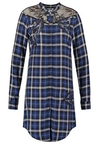 Robe-chemise à manches longues à carreaux bleu et blanc, avec empiècement en dentelle noire et appliques en sequins floraux sur la poitrine et le bas du côté. Boutons sur le devant.