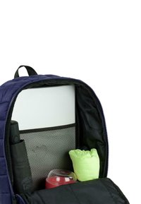 El interior de la mochila de la marina cuenta con un bolsillo de malla, un juguete verde, un contenedor rojo y un objeto cilíndrico negro. Forrada con tela negra.