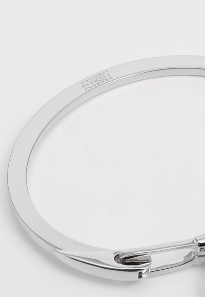 Silver bangle bracelet with smooth, rounded edges and a clasp. Features engraved numbers on the inner side. Reflective metallic finish.