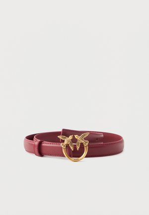Red leather belt with a gold circular buckle featuring two detailed birds facing each other.