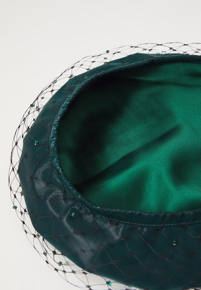 Roheline satiinvoodriga müts, millel on mustast võrgust kate, roheline pärlitega ning sileda tekstuuriga. Ümara kujuga ja kokku kogutud äärtega.