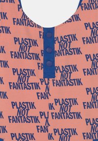 Tecido rosa com padrão apresentando o texto repetido "PLASTIK NOT FANTASTIK." A tapeta de botão azul na gola adiciona um contraste. Textura suave.