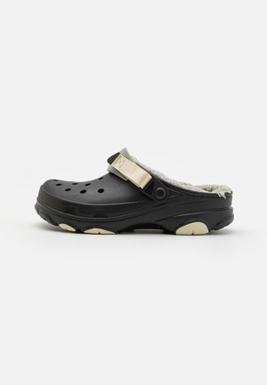 Chaussures noires avec bout et talon fermés, dotées de trous de ventilation, d'une doublure rembourrée et d'une sangle contrastante pour un ajustement réglable.