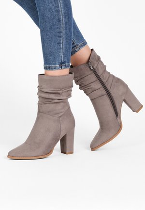 Grå ruskindsankelstøvler med slasket design, spids tå og 10 cm blokhæl, med en sideslynge til lukning.