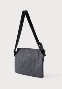 Szara prostokątna torba na ramię z czarnym regulowanym paskiem i subtelnym geometrycznym wzorem z małymi logo projektanta.