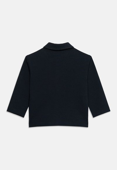 Μαύρο cropped μπουφάν με μακριά μανίκια και φαρδιά γιακά, εμφανιζόμενο από πίσω σε απλό ανοικτό φόντο.