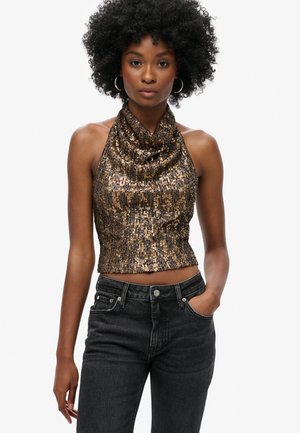 Top corto de halter en tonos metálicos de marrón y dorado, decorado con lentejuelas, con un escote drapeado. Combinado con jeans oscuros, creando un aspecto texturizado y en capas.