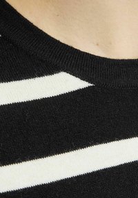 Sort og creme stribet strikket stof med en rund halsudskæring. Teksturen er glat med synlige strikkemønstre og ensartet stribete alignment.