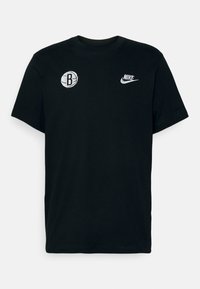 Camiseta de algodón negra con mangas cortas. Presenta un logo de baloncesto blanco con una "B" y un logo de la marca Nike en lados opuestos.