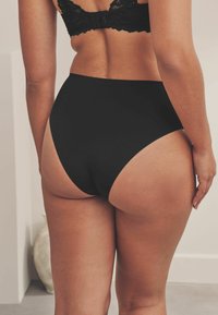 Hoge taille zwarte slipjes van een gladde stof, met een naadloos ontwerp, middelhoge snit en minimale stiksels voor een nette afwerking.