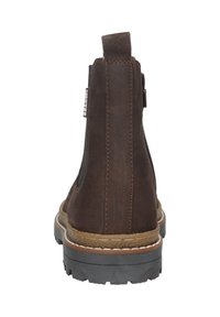 Bottine en cuir marron avec languette, couture visible et semelle épaisse en caoutchouc noir, vue de l'arrière.
