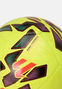 Puma nogometna žoga, svetlo rumena z črnimi in vijoličnimi geometrijskimi vzorci, z gladko sintetično površino in detajlom logotipa.