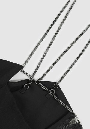 Schwarze Stofftasche mit Kettenriemen, ausgestattet mit Metallbeschlägen, einem Reißverschluss und einer Innentasche. Glatte Textur, minimalistisches Design.