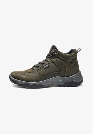 Dunkelgrüner knöchelhoher Wanderschuh mit schwarzen Schnürsenkeln, gepolstertem Knöchelbereich, dicker grauer Sohle und Gore-Tex-Label an der Seite.