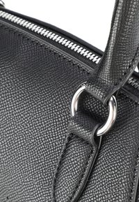 Czarna torebka skórzana o fakturowanej powierzchni z metalowym zamkiem błyskawicznym i pierścieniowymi elementami. Uchwyt ozdobiony jest dopasowanym skórzanym paskiem.