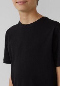 Schwarzes Baumwoll-T-Shirt mit Rundhalsausschnitt und kurzen Ärmeln, das eine glatte Textur und genähte Details an den Kanten aufweist.