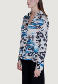 Langärmliges Button-up-Hemd aus leichtem Stoff mit einem blauen, schwarzen und beigen abstrakten Muster, lockerem Schnitt und offenem Kragen.
