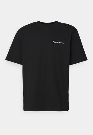 T-shirt noir à manches courtes et col rond avec un petit logo blanc "Filling Pieces" sur le côté gauche de la poitrine.